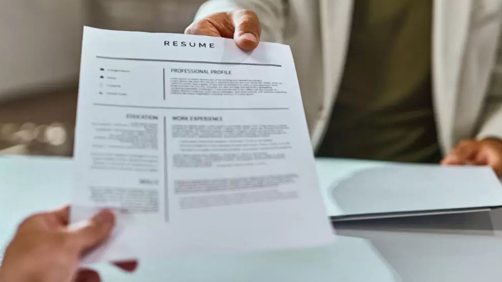 Duas pessoas passando um currículo uma para a outra