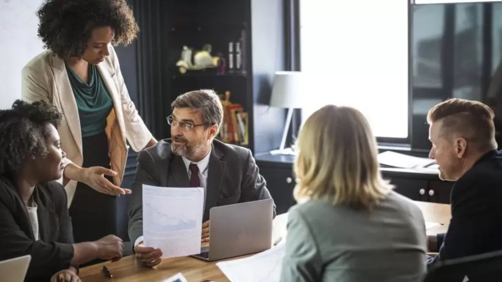 Um grupo de pessoas entre homens brancos e mulheres brancas e negras conversando no trabalho