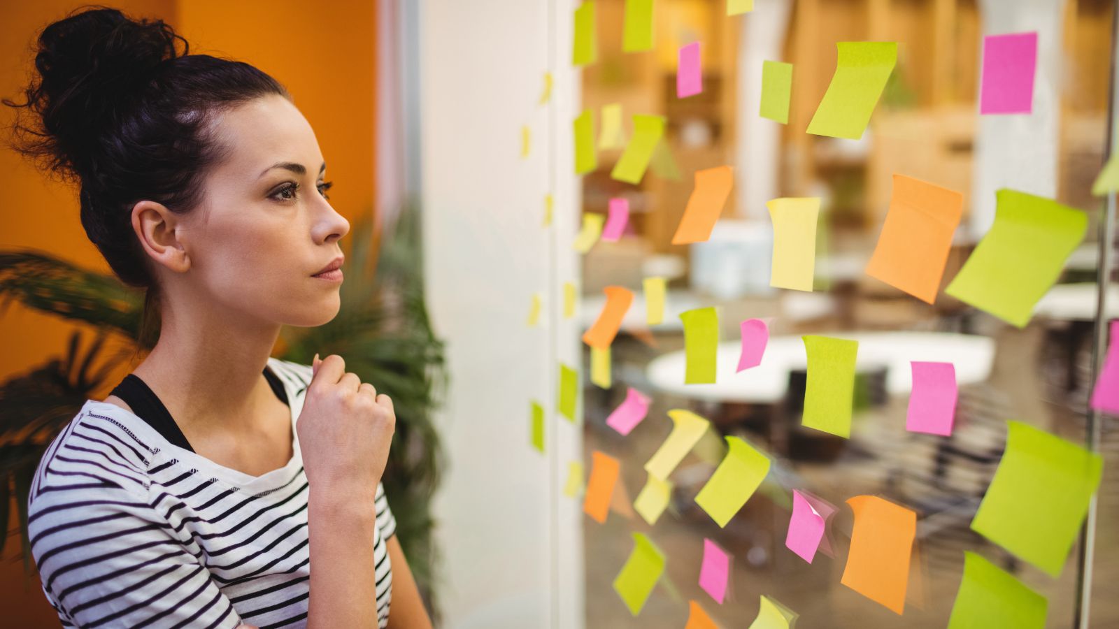 Mulher olhando para post it no serviço