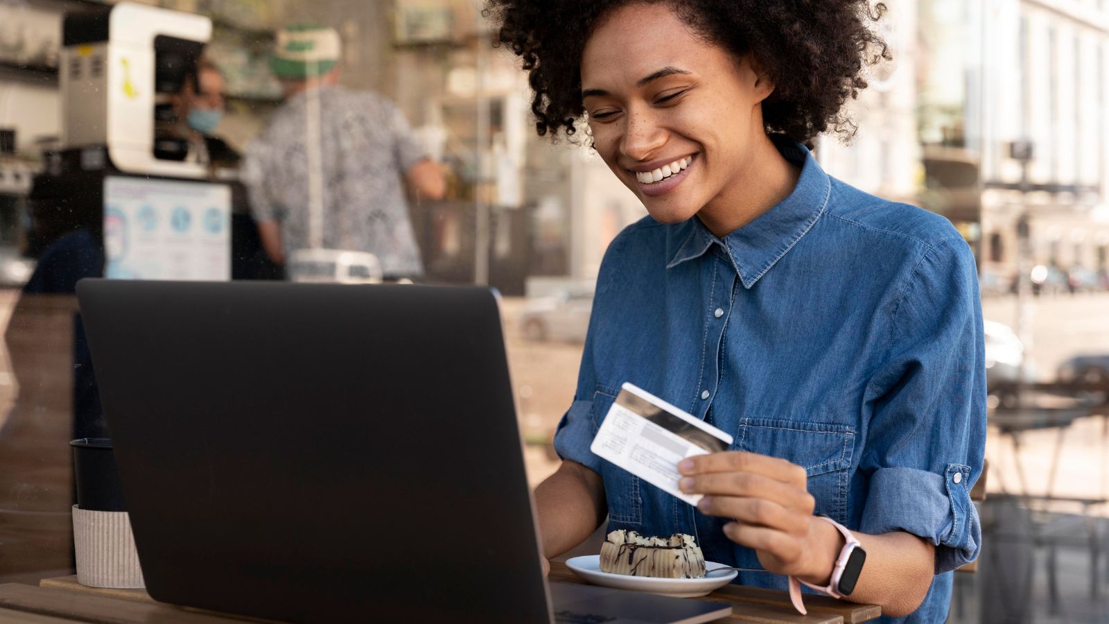 Mulher segurando cartão mexendo em computador
