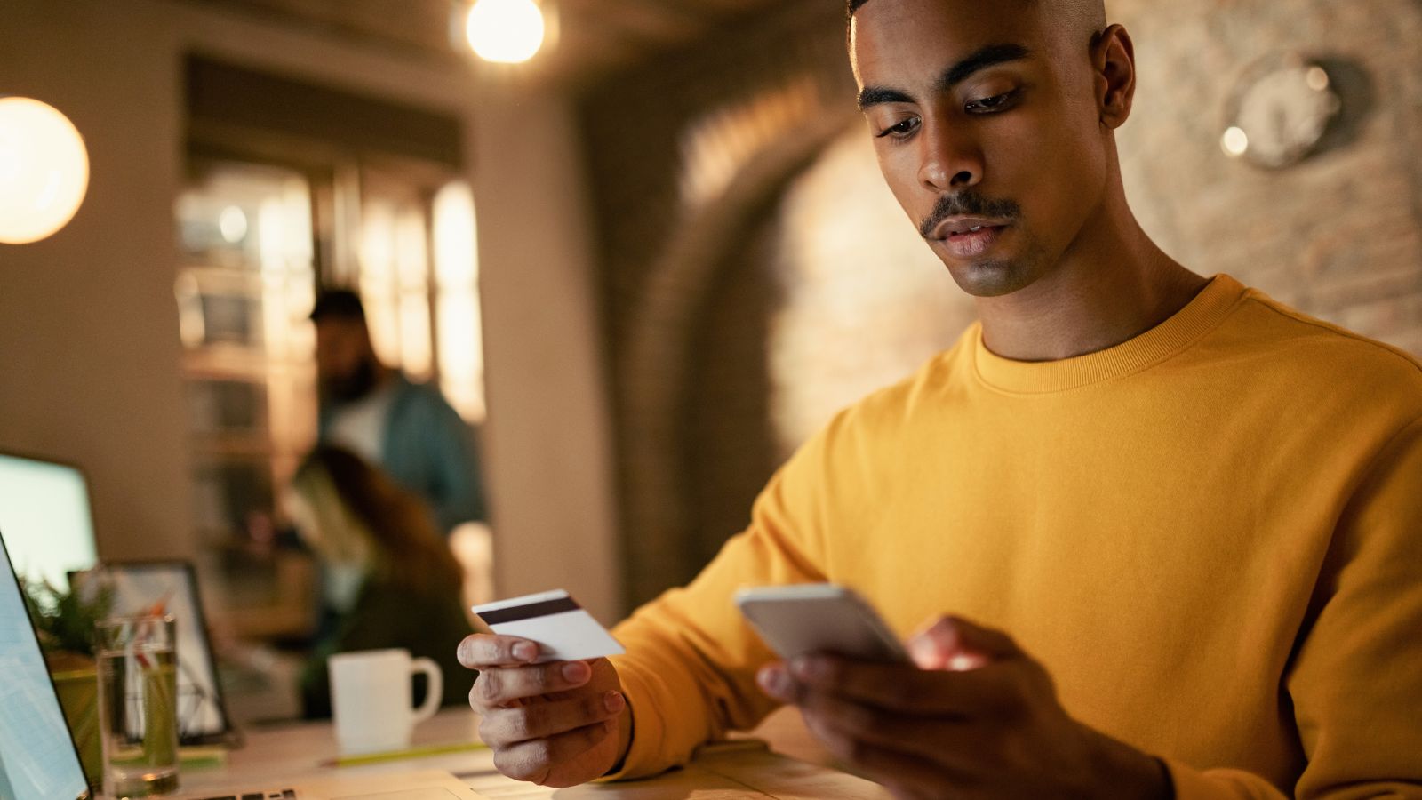 Homem segurando cartão e o celular