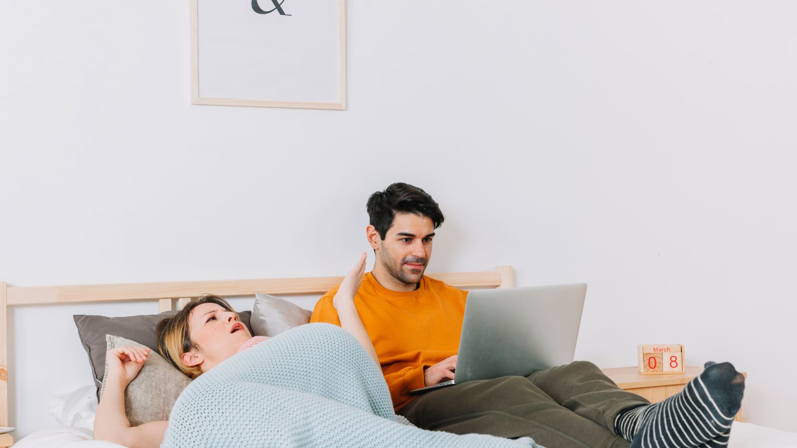 Mulher discutindo com homem com laptop na cama