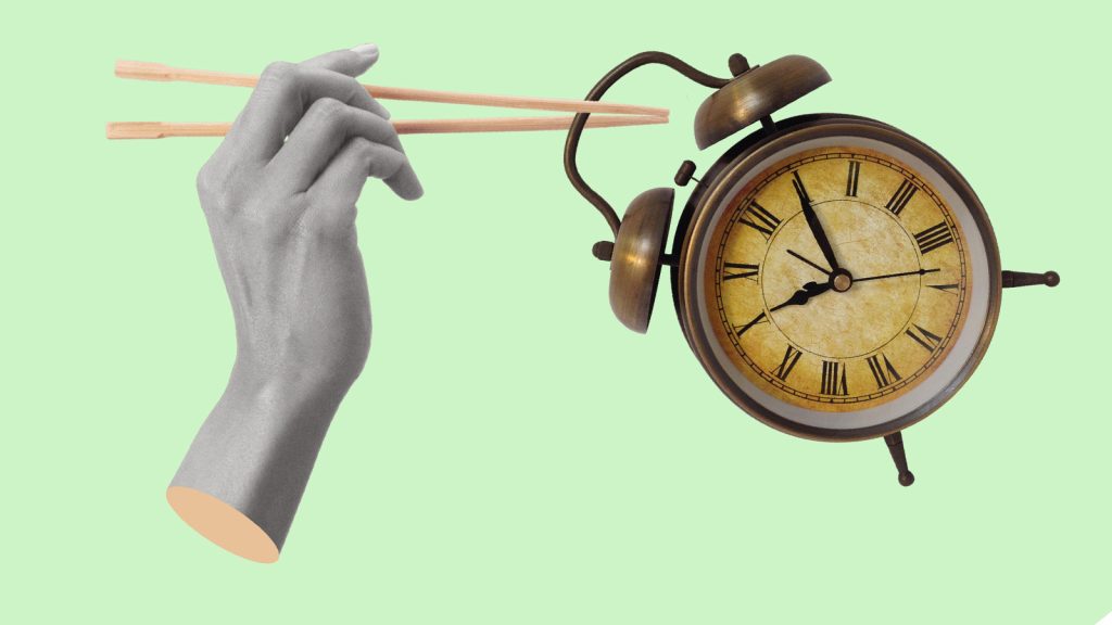 controle do tempo: mão tenta pegar despertador com hashis