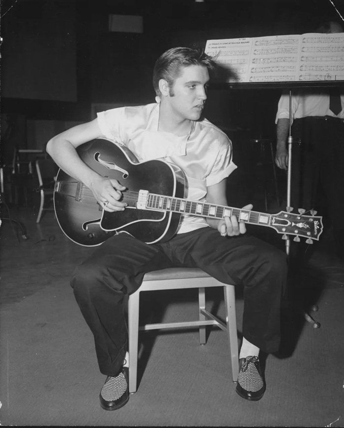 imagem em preto e branco de Elvis Presley jovem com seu violão