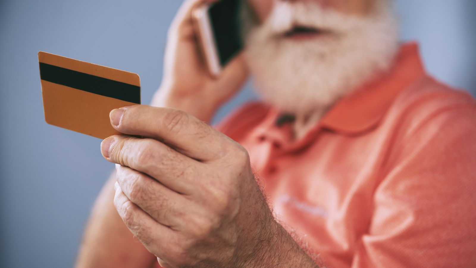 Idoso segurando cartão e falando no celular