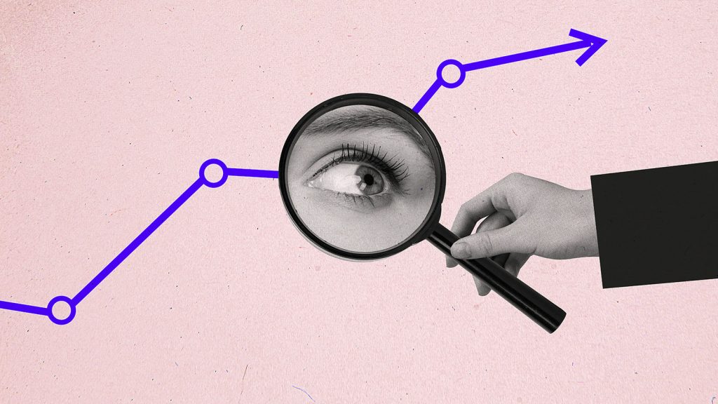 em fundo rosa, mão segura lupa que reflete a imagem de um olho