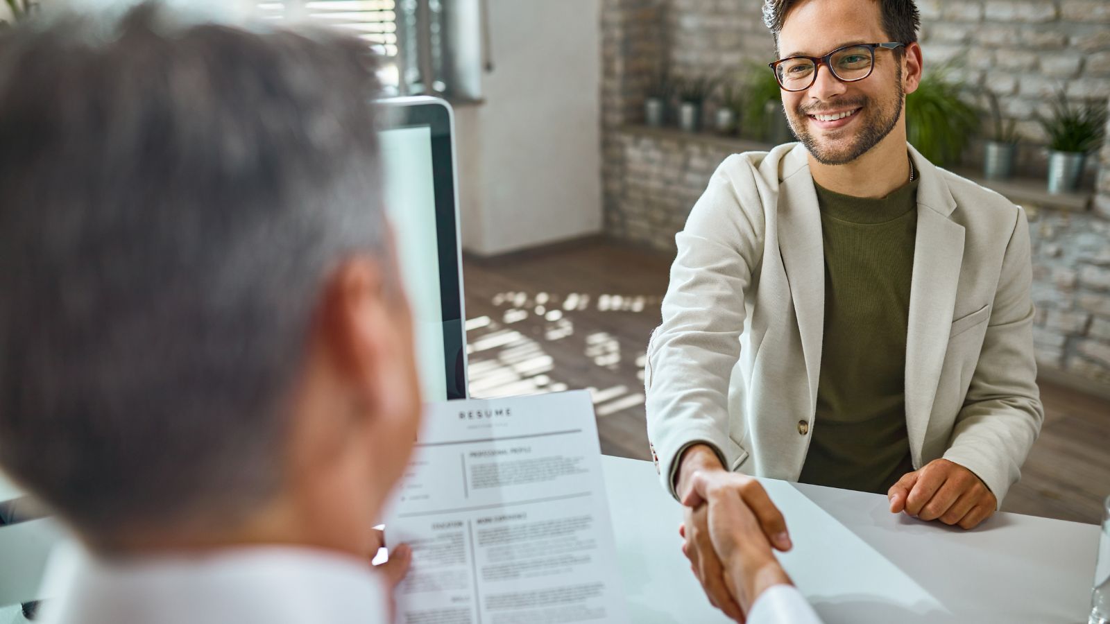 Jovem apertando mão de gestor em entrevista de emprego