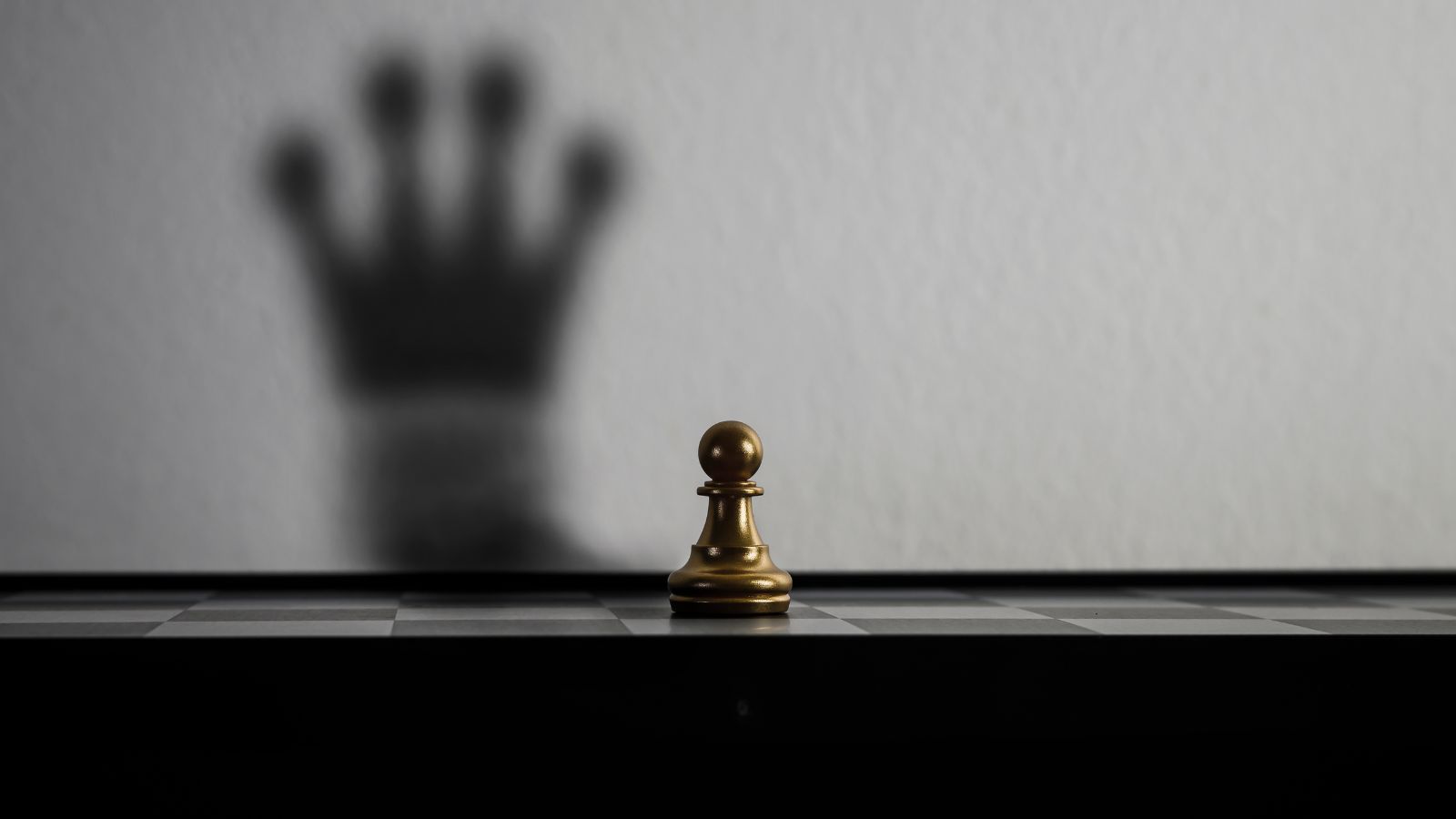 Peão de xadrez olhando sombra de rainha ao fundo