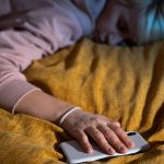 Mulher dormindo com celular na mão