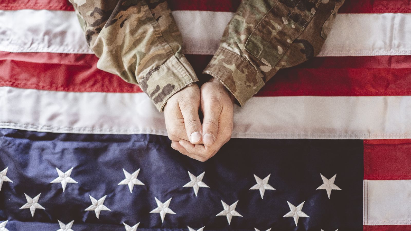 Mão de soldado em cima de bandeira dos EUA
