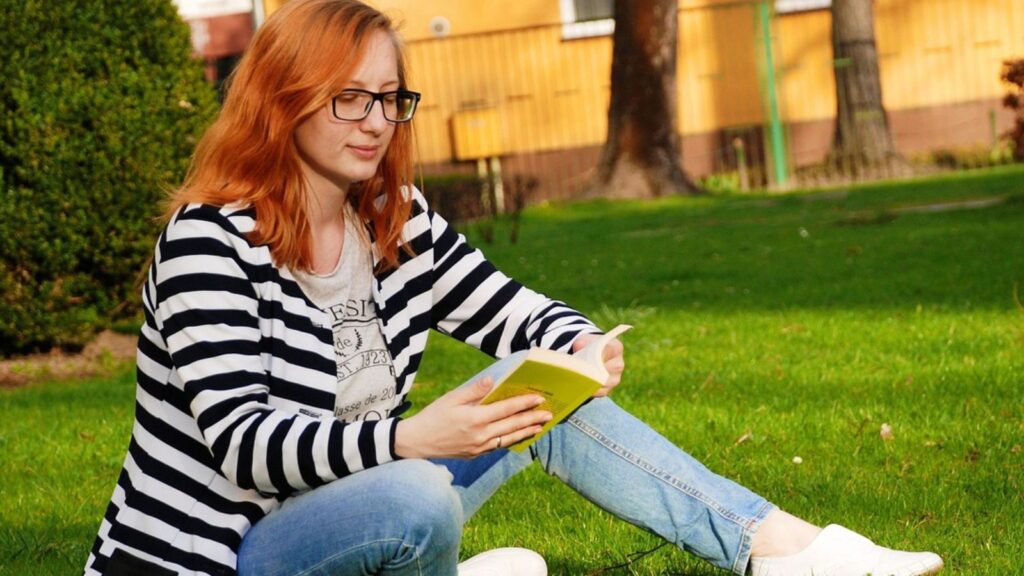 Mulher lendo livro na grana