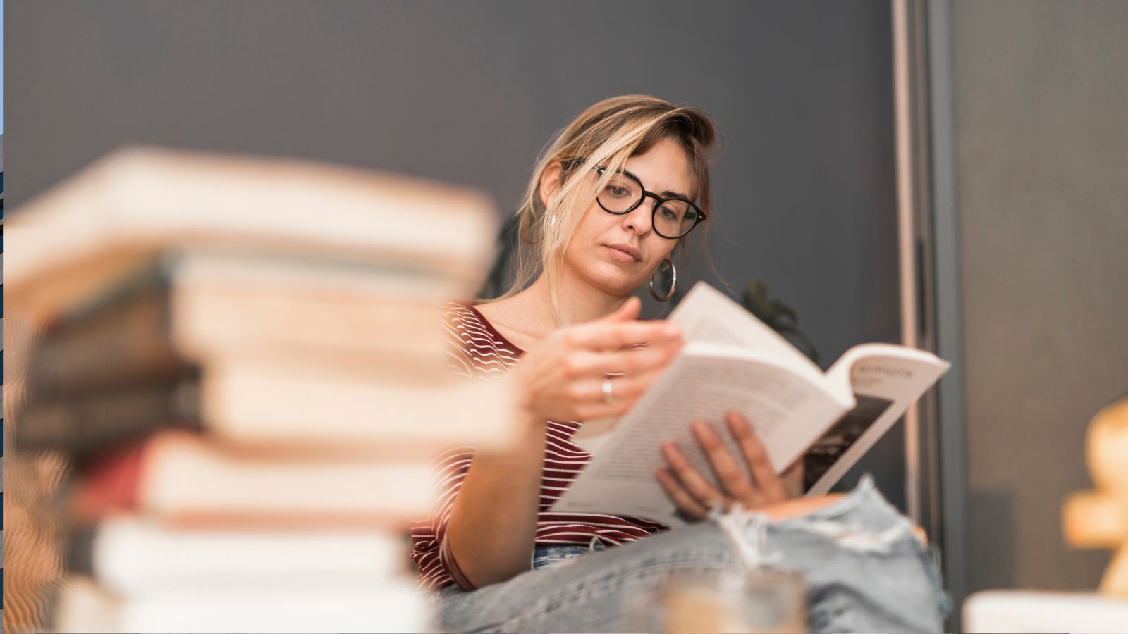 Mulher lendo livro e pilha de livros a frente