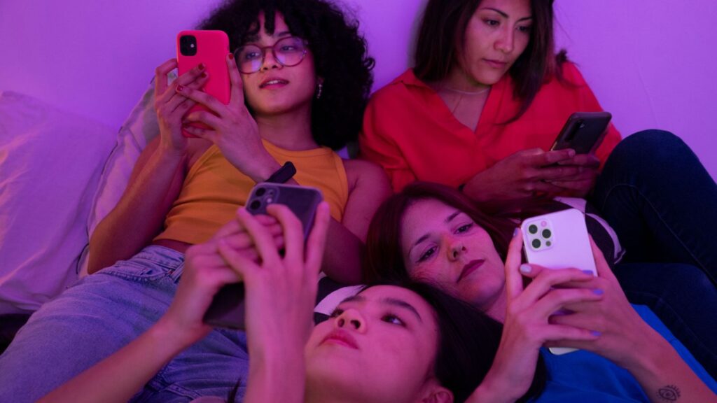 Jovens sentadas mexendo em celular