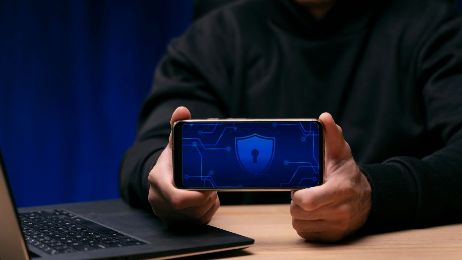 Pessoa de capuz segurando celular