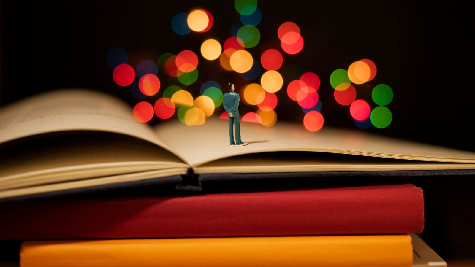 Pilha de livros com boneco em cima