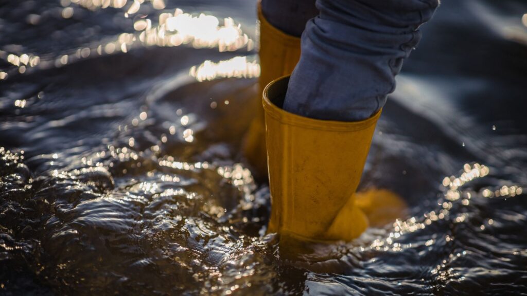 Pessoa com botas amarelas de chuva na enchente
