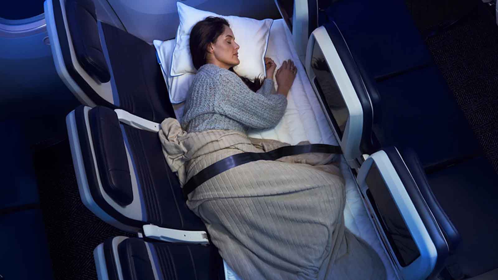 mulher deitada em uma fileira de poltronas do avião, feitas para se transformarem em cama
