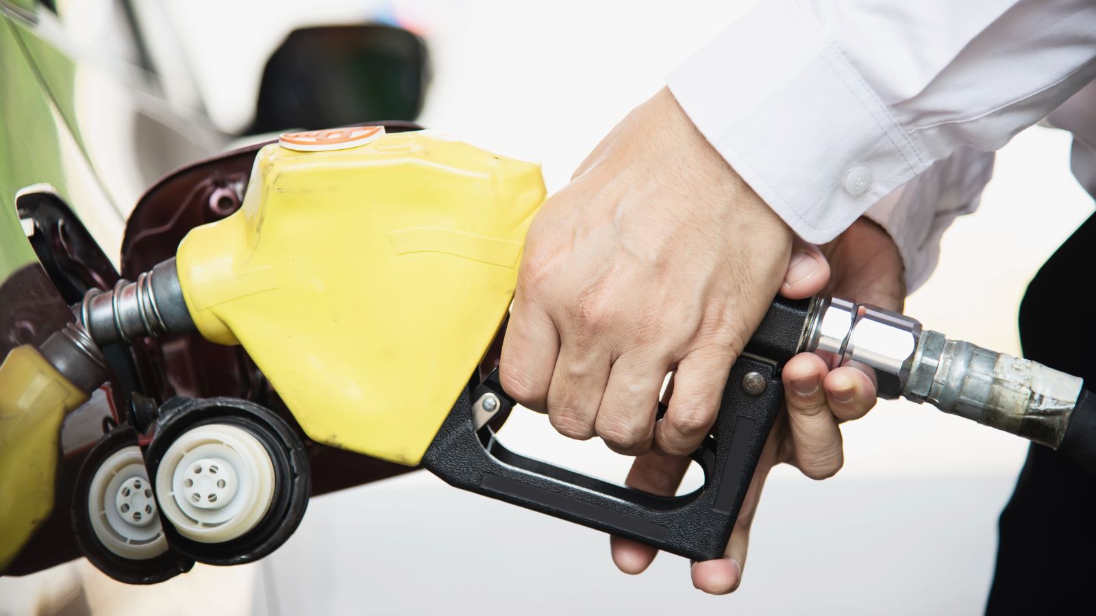 homem segurando a mangueira de gasolina e abastecendo o carro