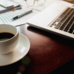 Xícara de café com notebook no fundo