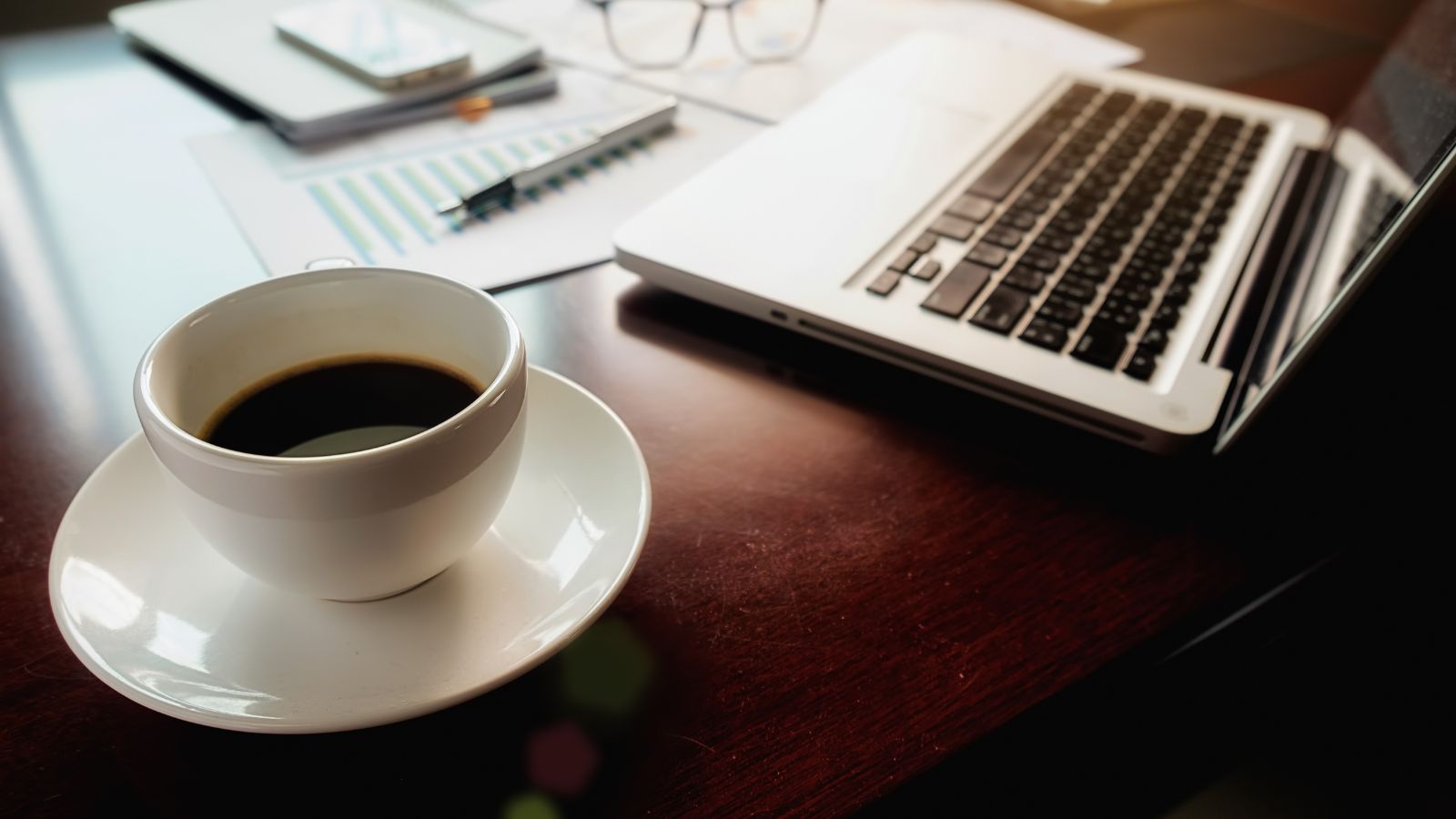 Xícara de café com notebook no fundo