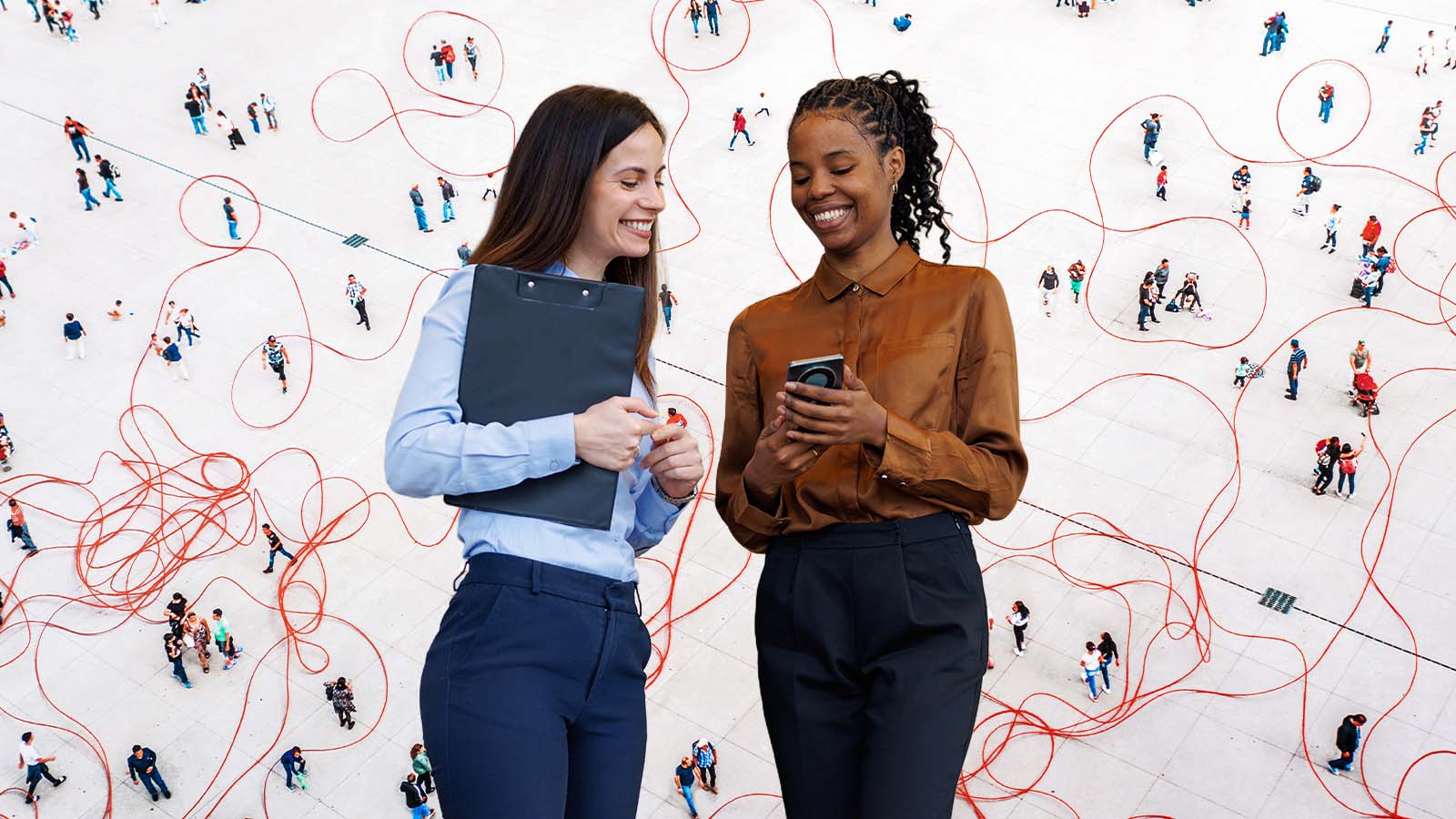 Duas profissionais sorriem enquanto conversam e olham para um celular, diante de uma praça vista de cima com pessoas conectadas por linhas vermelhas. A imagem sugere networking, análise de comportamento coletivo, redes sociais, dados de mobilidade ou conexões humanas mediadas por tecnologia.