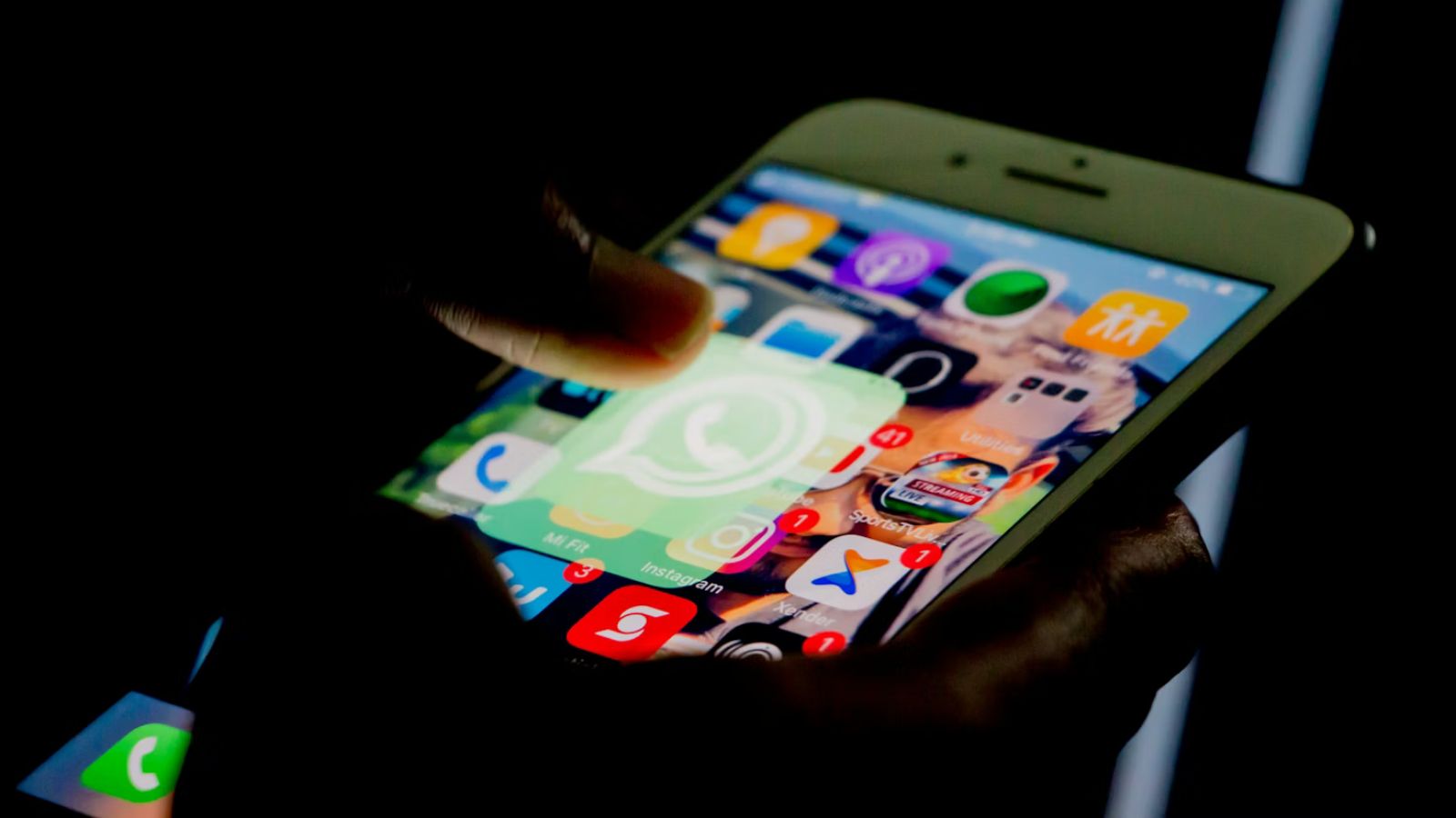 Mão mexendo no celular com o logo do Whatsapp na tela