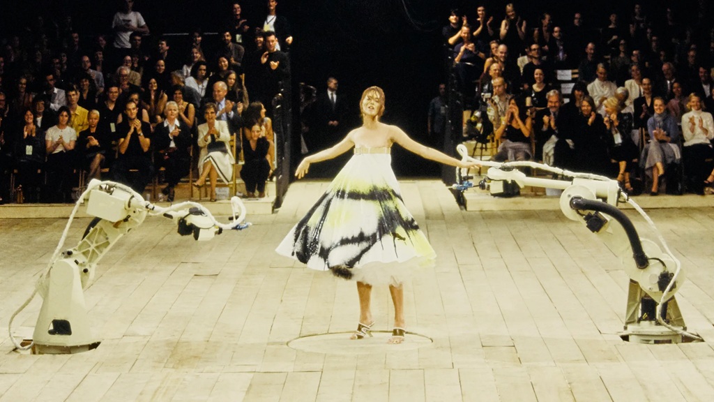 bra&ccedil;os mec&acirc;nicos espalham tinta em vestido branco em desfile da cole&ccedil;&atilde;o de Alexander McQuenn em 1999