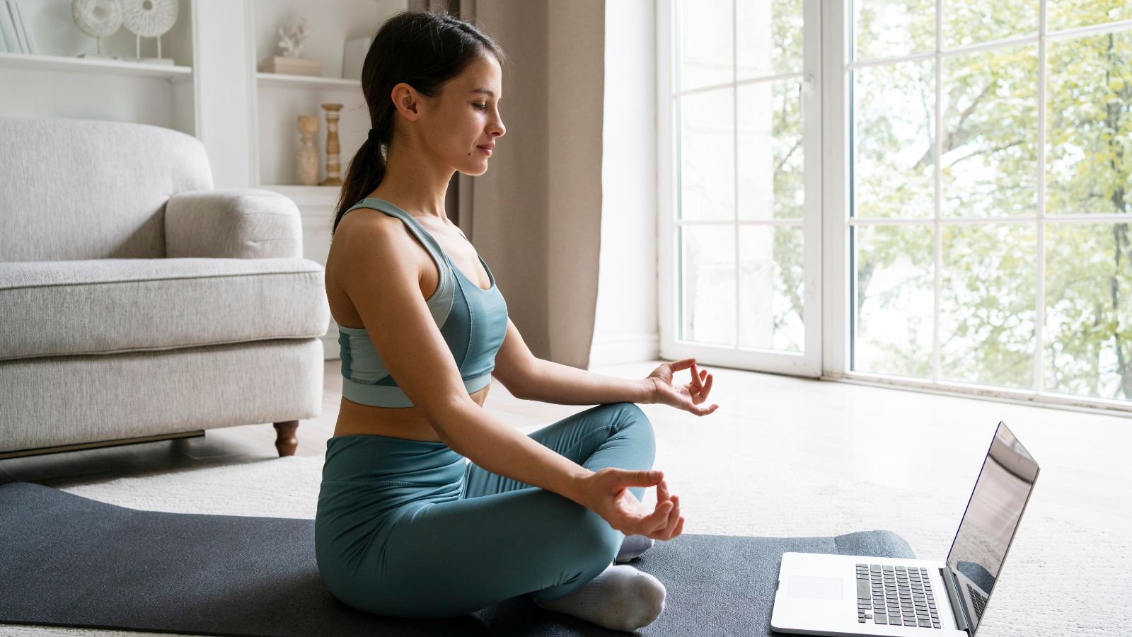 Mulher meditando em rente a um notebook.