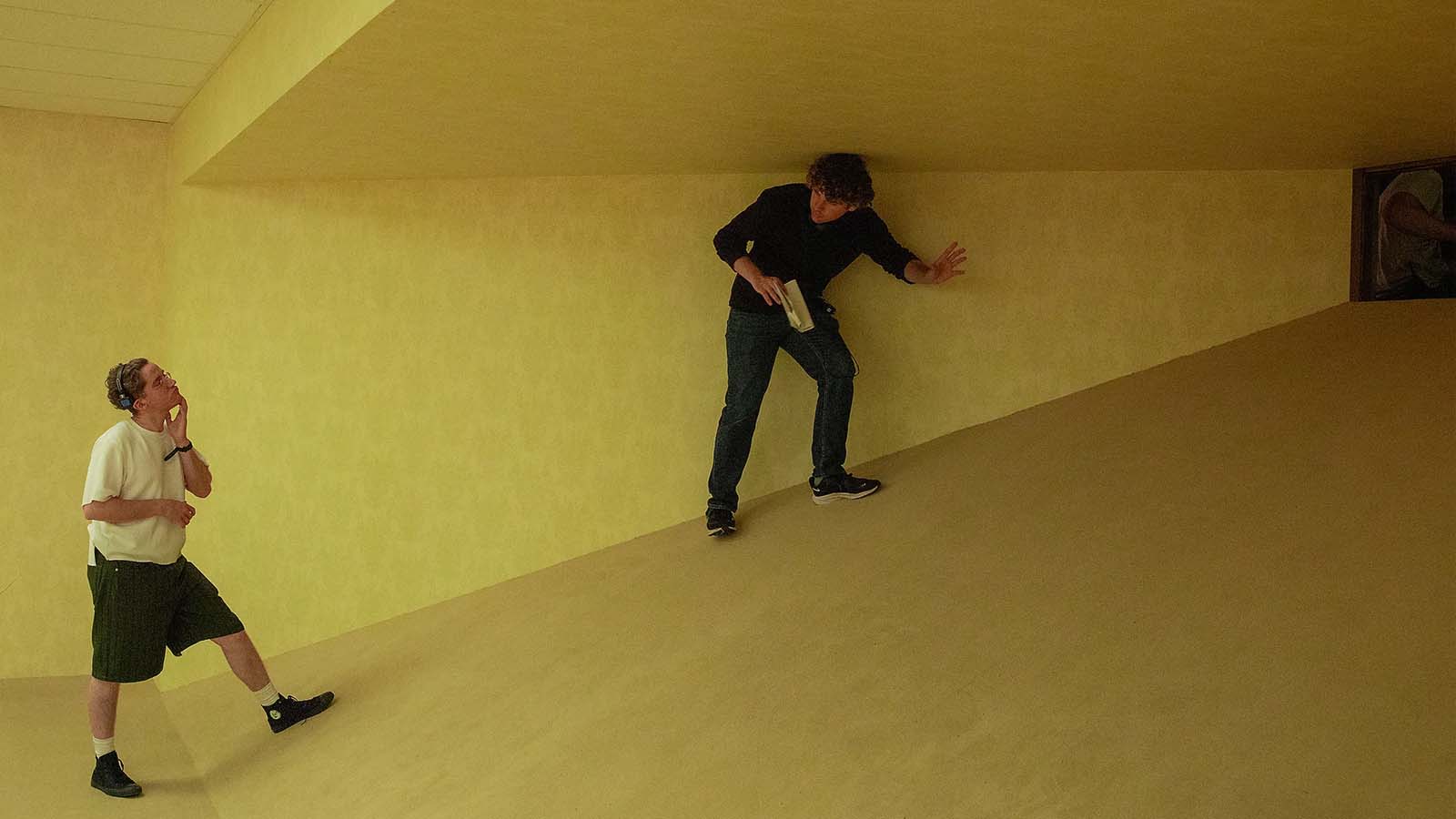 Membros da equipe de produção caminham por um cenário inclinado criado para representar o Backrooms no novo filme da A24.