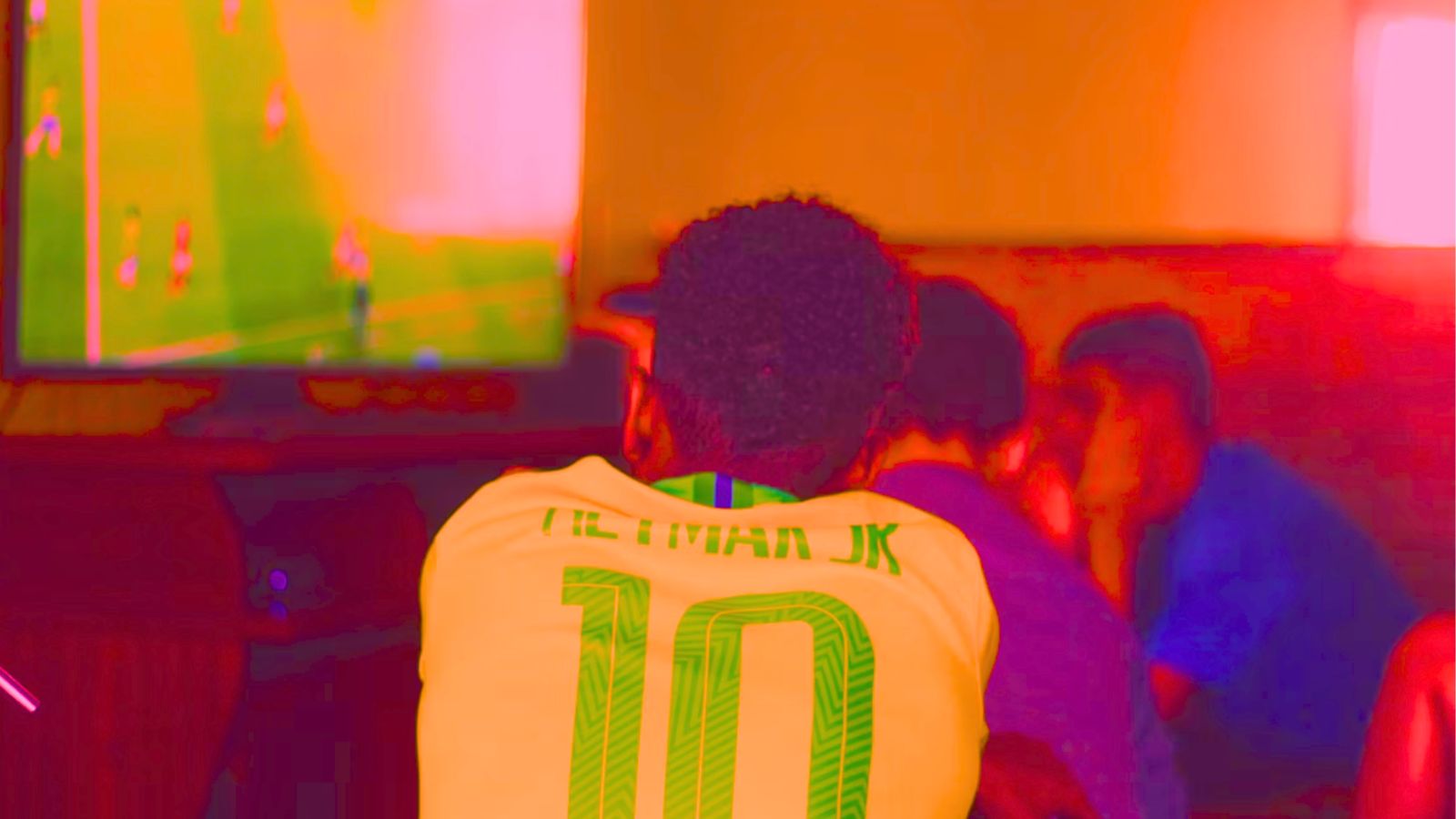 Pessoa assistindo futebol com a camisa do Brasil