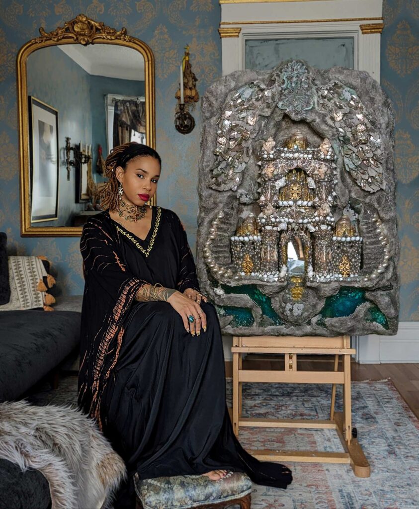 A artista haitiana Fabiola Jean-Louis posa ao lado de uma escultura ornamentada com pérolas e elementos metálicos