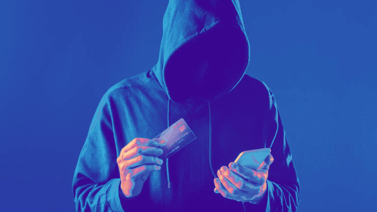 Homem de capuz segurando celular e cartão em fundo preto