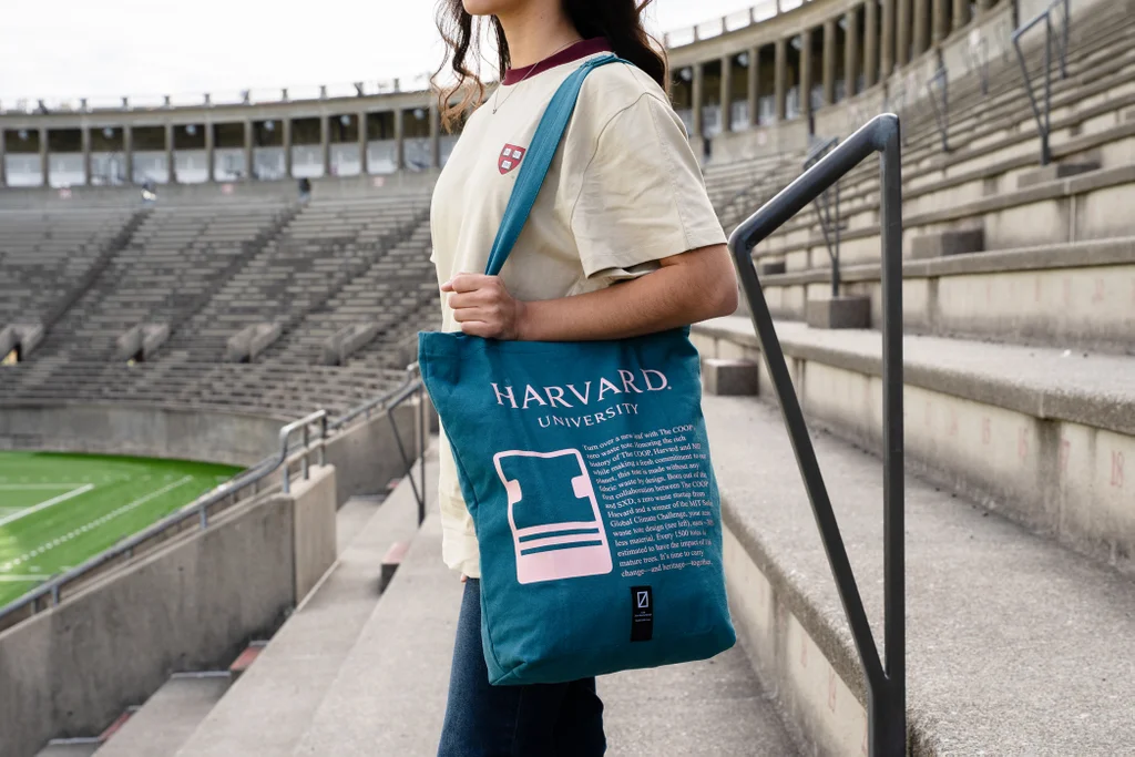Estudante carrega uma sacola azul da Harvard University criada pela SXD com t&eacute;cnicas de produ&ccedil;&atilde;o sem desperd&iacute;cio.