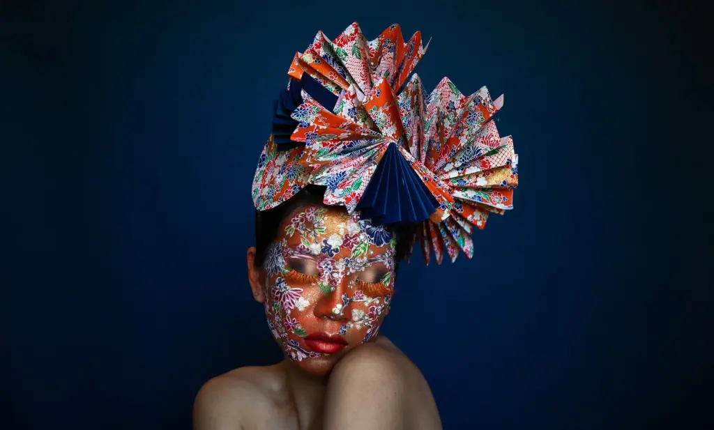 Cindy Chen posa com o rosto pintado com padr&otilde;es florais e um adere&ccedil;o de pap&eacute;is coloridos dobrados sobre a cabe&ccedil;a.