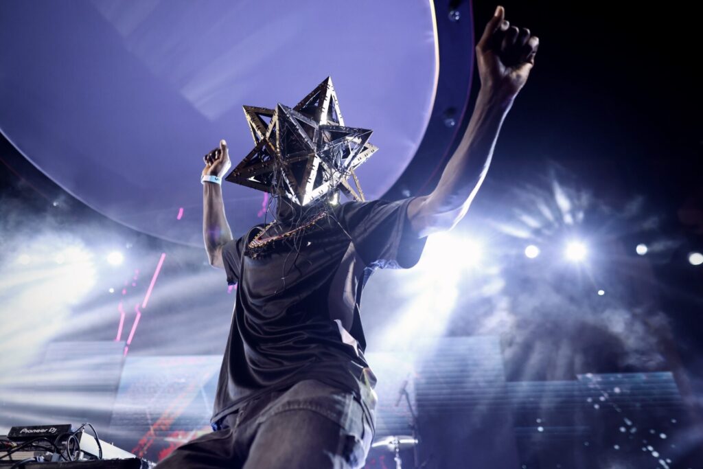 Artista se apresenta no palco usando uma m&aacute;scara em formato de estrela durante o Festival MARTE 2026.