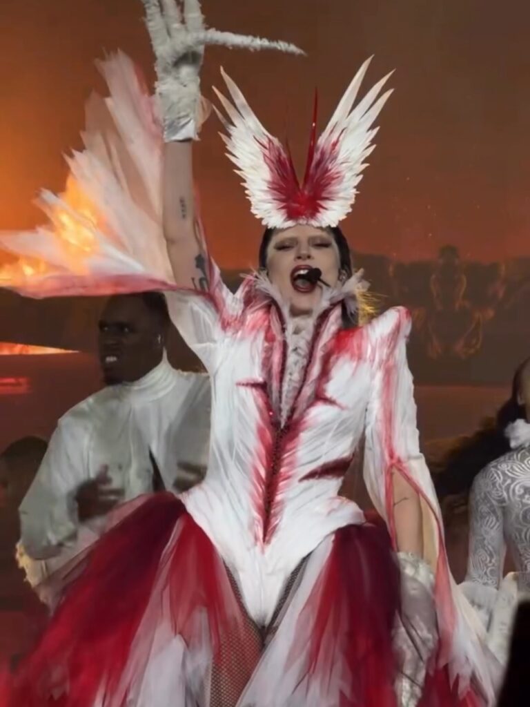 Lady Gaga se apresenta com figurino branco e vermelho com penas criado pela Matières Fécales.