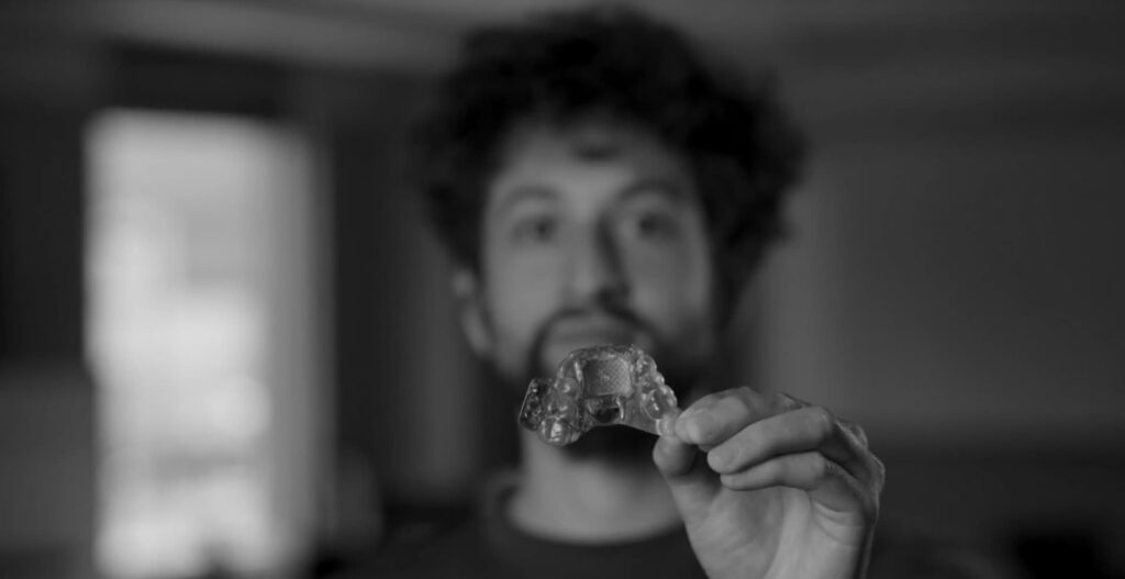 Homem segura um pequeno MouthPad transparente diante da c&acirc;mera.