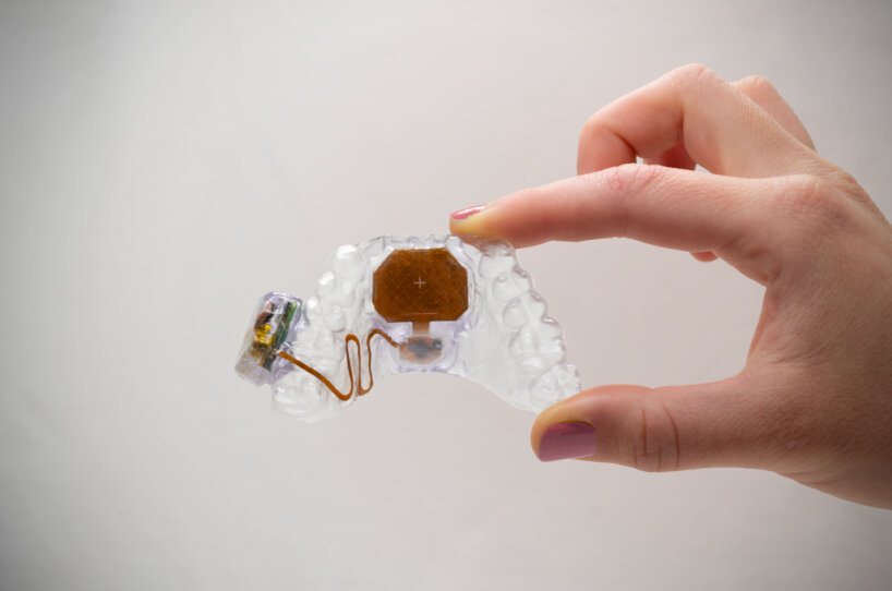 M&atilde;o segura o pequeno MouthPad transparente entre os dedos.