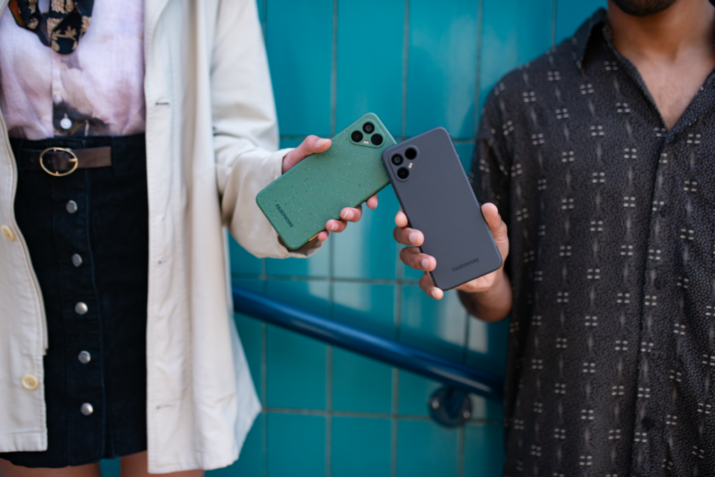 Duas pessoas seguram modelos do Fairphone nas cores verde e cinza.