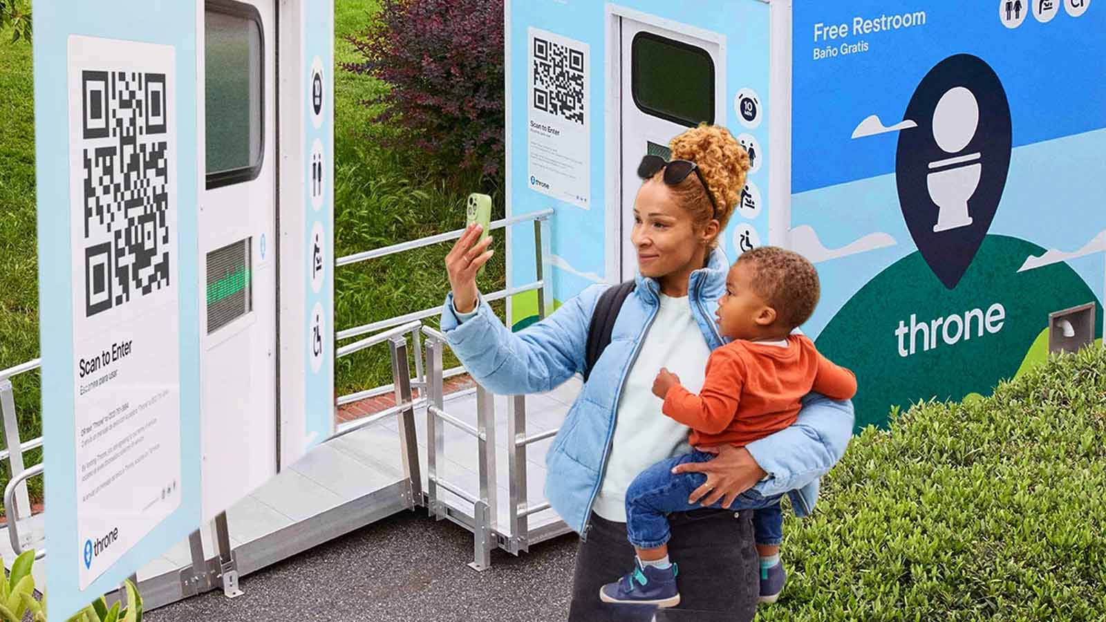 Mulher segura criança e usa celular para acessar banheiro-robô da Throne Labs por QR Code.
