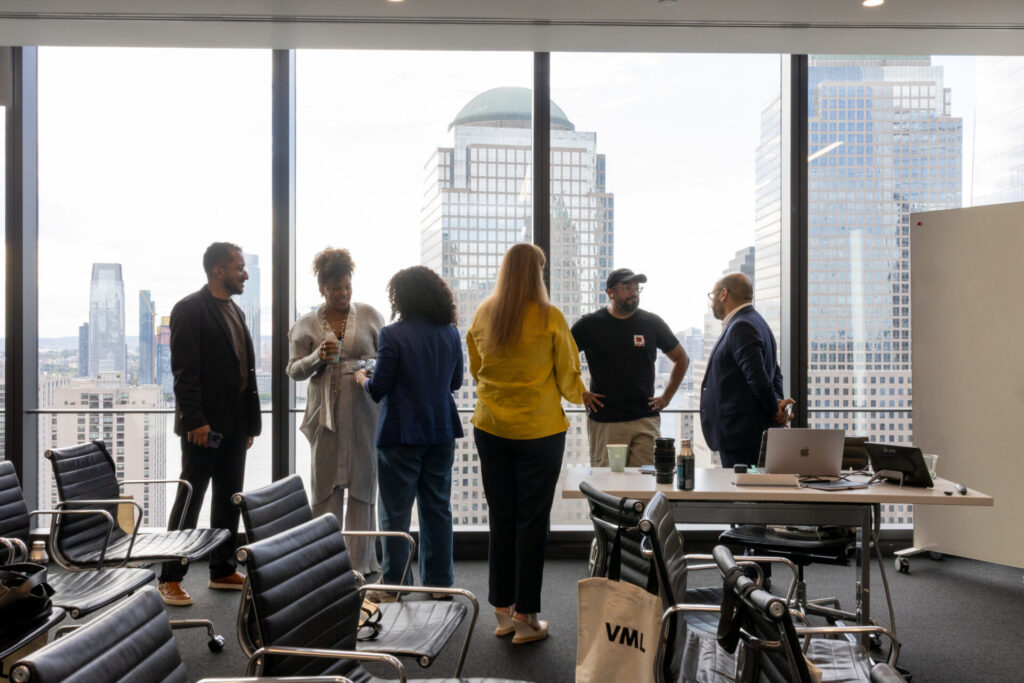 Participantes do lançamento da AZO conversam em uma sala de reuniões com vista para Nova York.