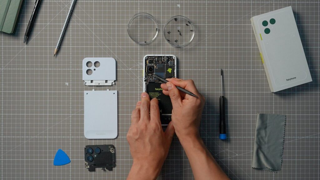 Fairphone aberto sobre uma bancada, cercado por ferramentas, parafusos e componentes remov&iacute;veis.