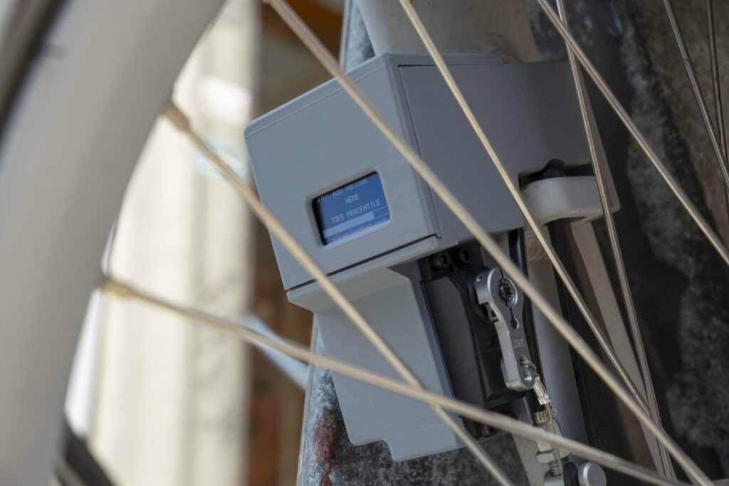 Dispositivo Ground Truth preso &agrave; roda de uma bicicleta exibe o indicador de press&atilde;o do aluguel no bairro.