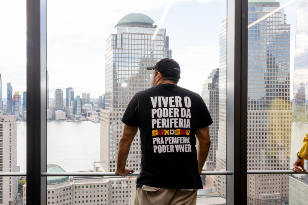 Participante do lançamento da AZO observa Nova York usando uma camiseta com a frase “Viver o poder da periferia”.