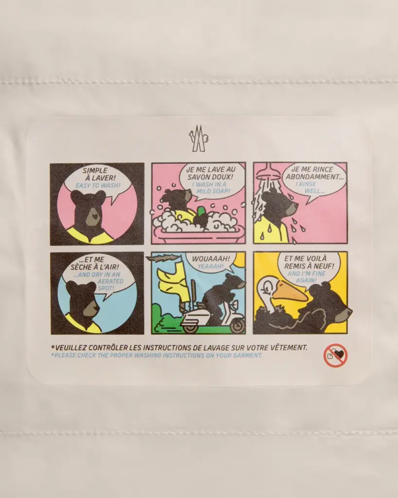 Etiqueta interna de um casaco mostra instru&ccedil;&otilde;es de lavagem em seis quadrinhos coloridos protagonizados por um urso.
