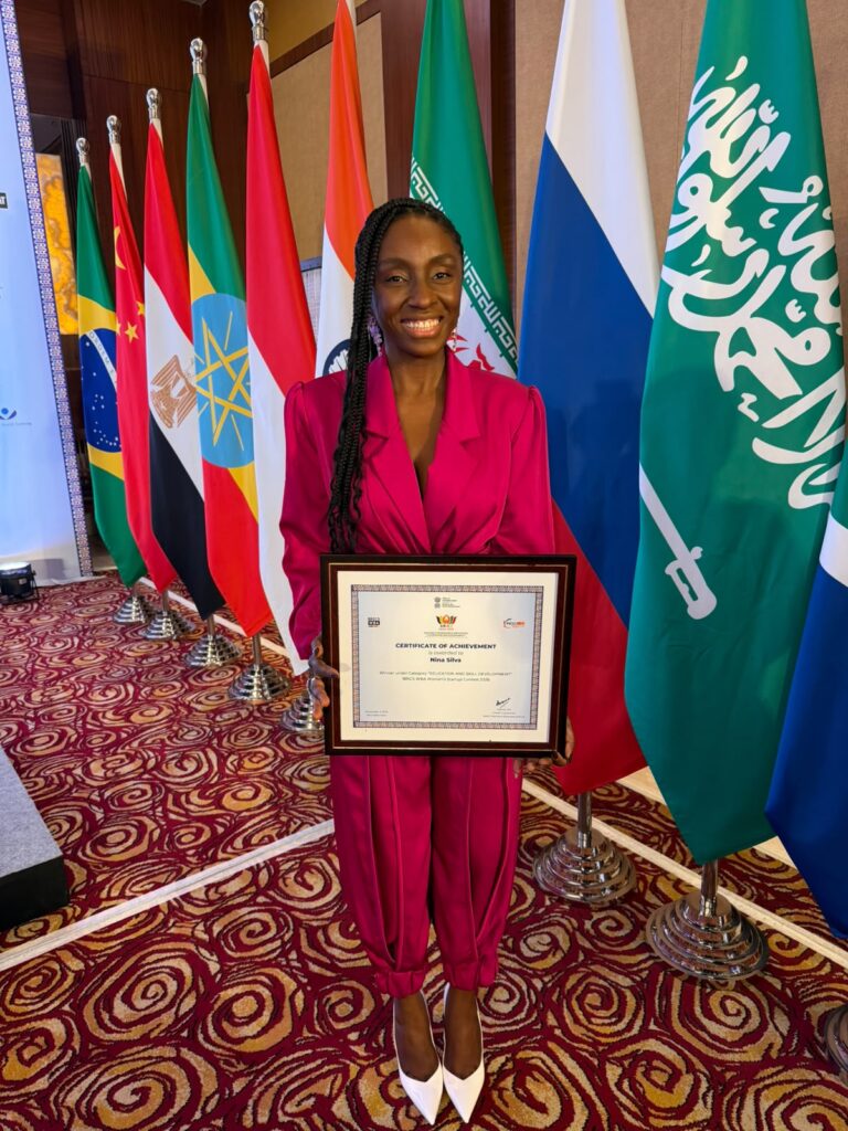 Nina Silva segura um certificado diante das bandeiras de países do Brics.