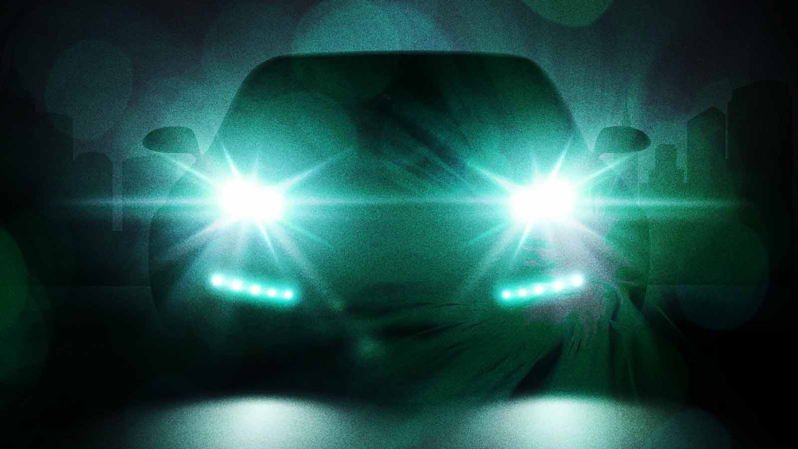 Carro visto de frente, em ambiente escuro, com luzes azul-esverdeadas acesas.
