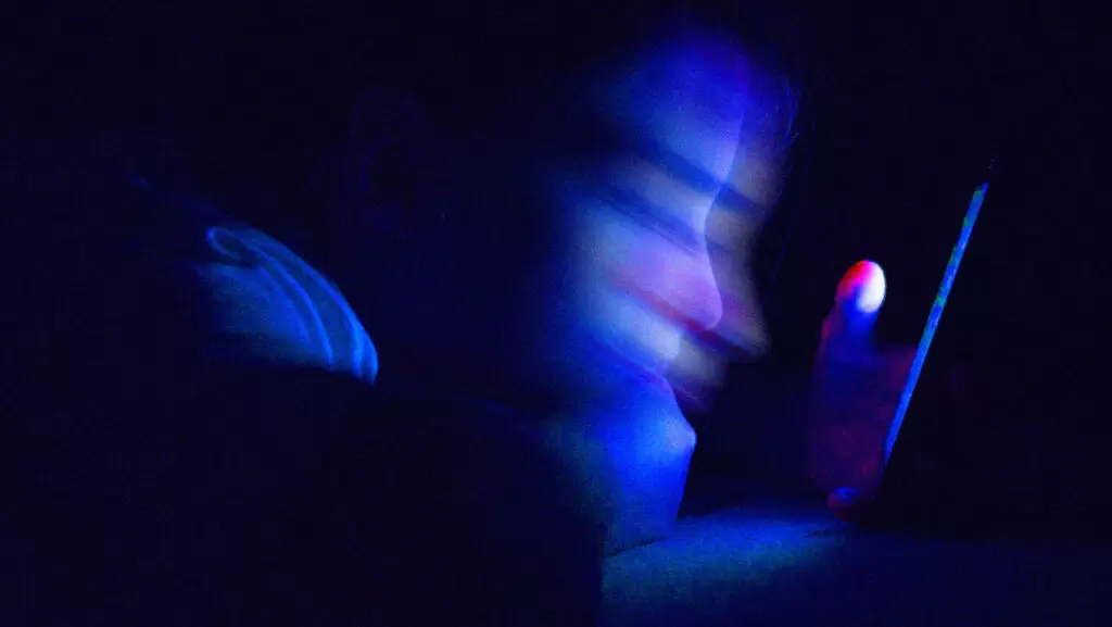 imagem borrada de rosto de crian&ccedil;a olhando para o celular