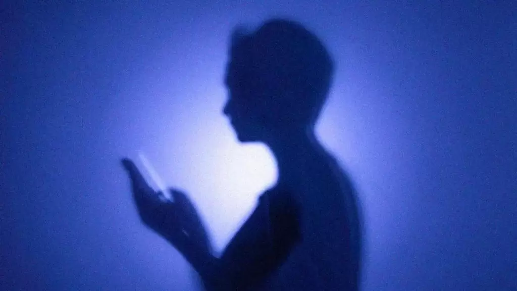 Silhueta de uma pessoa segurando um celular nas mãos