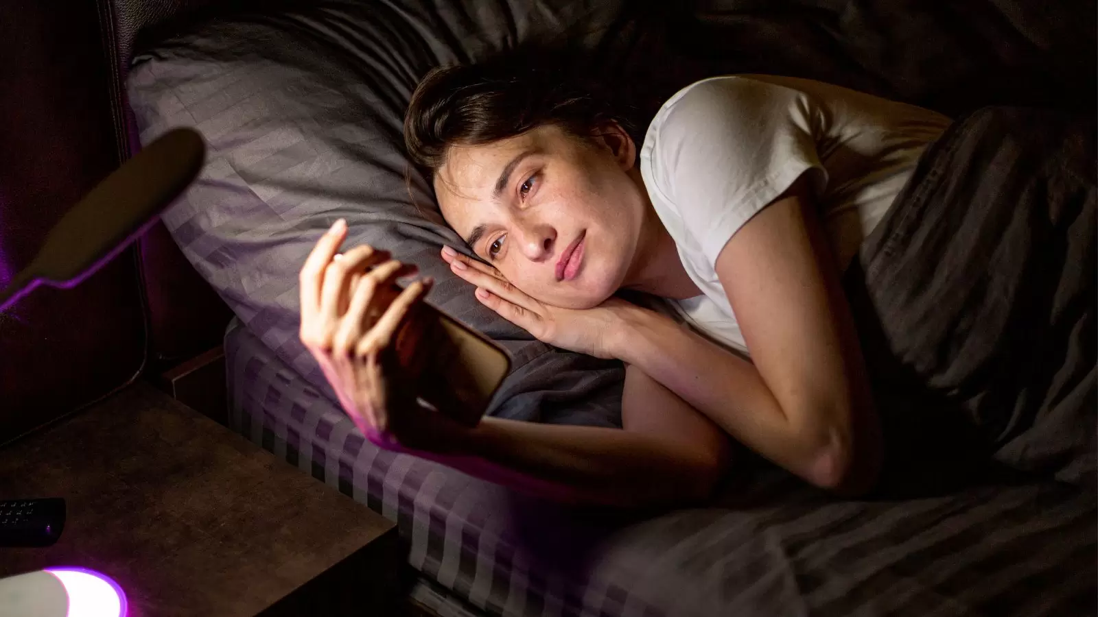 Mulher mexendo no celular na cama